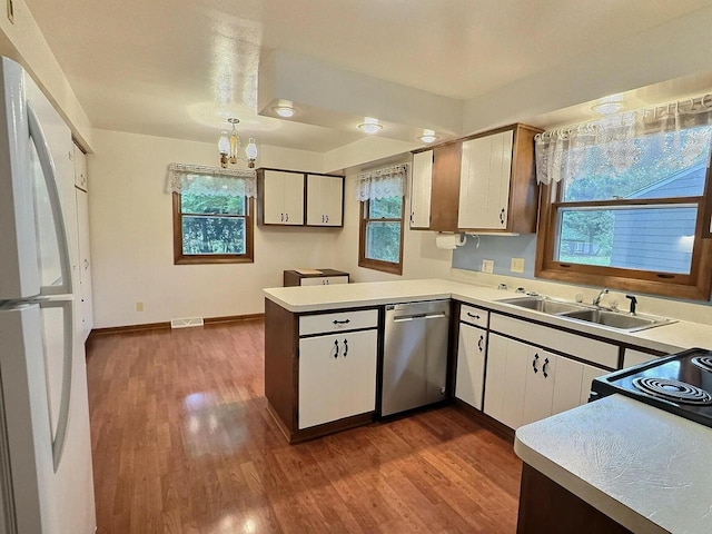 525 Pembrook Ct, Neenah, WI 54956 - kitchen featuring stainless steel dishwasher, freestanding refrigerator, a peninsula, dark wood finished floors, and white cabinets