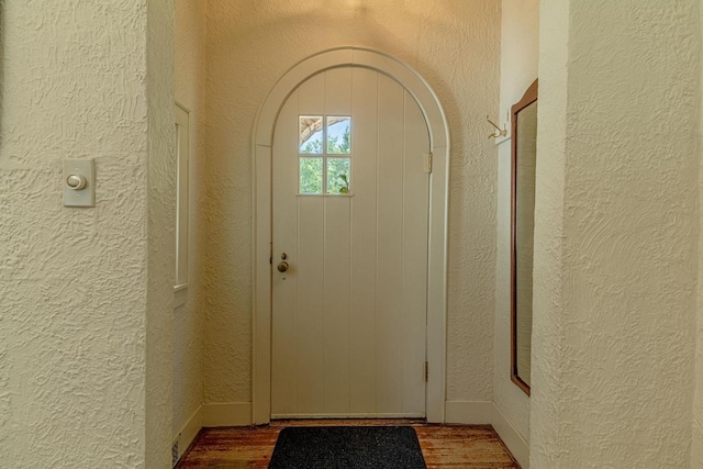 1329 23rd Ave, Monroe, WI 53566 - doorway to outside with a textured wall, wood finished floors, and arched walkways