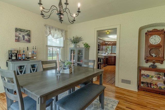1329 23rd Ave, Monroe, WI 53566 - dining room featuring a textured wall, a chandelier, light wood-style flooring, and arched walkways