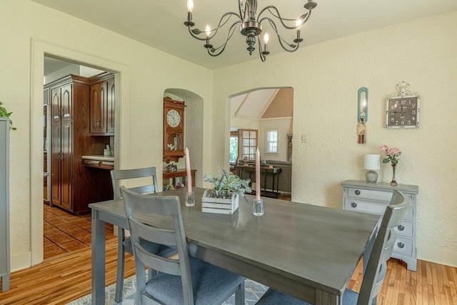 1329 23rd Ave, Monroe, WI 53566 - dining room featuring arched walkways, a chandelier, a textured wall, and light wood finished floors