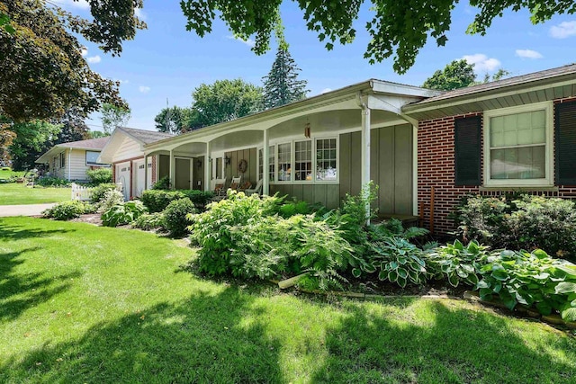 435 S Main St, Markesan, WI 53946 - view of side of home with board and batten siding, a yard, a garage, brick siding, and driveway