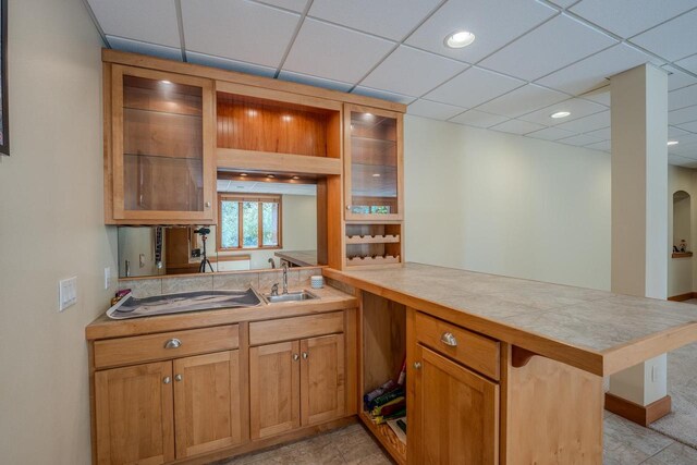 303 Rimrock Rd, Wausau, WI 54401 - kitchen featuring a peninsula, light countertops, a drop ceiling, glass insert cabinets, and a breakfast bar