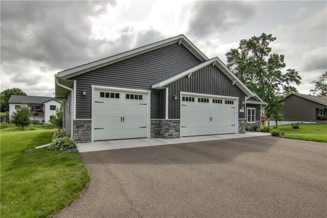 2247 105th St, Eau Claire, WI 54703 - view of front facade with stone siding, a front lawn, driveway, board and batten siding, and a garage