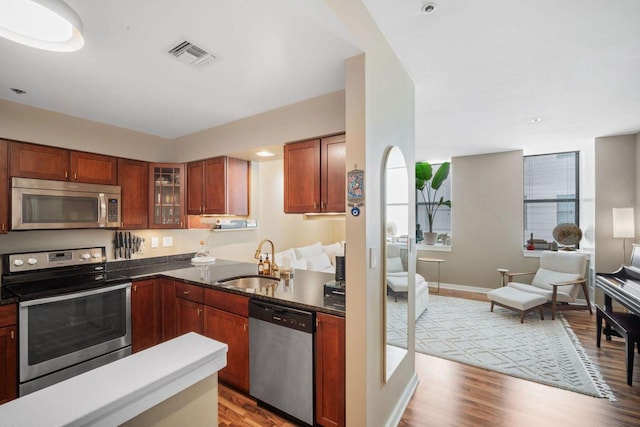 234 N Broadway Unit 402, Milwaukee, WI 53202 - kitchen with stainless steel appliances, light wood-style flooring, open floor plan, glass insert cabinets, and brown cabinetry