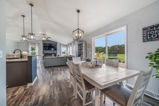 N3366 Flynn Dr, Montello, WI 53949 - dining area with dark wood-type flooring, lofted ceiling, a ceiling fan, a chandelier, and a glass covered fireplace