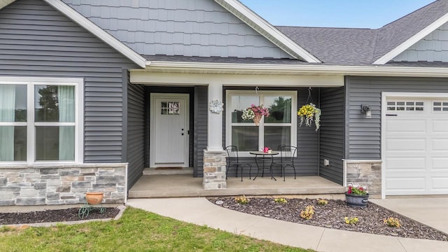 N3366 Flynn Dr, Montello, WI 53949 - doorway to property featuring a porch, stone siding, an attached garage, and roof with shingles
