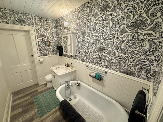 303 E 5th St, Washburn, WI 54891 - full bathroom featuring wallpapered walls, wainscoting, wood finished floors, a tub, and vanity