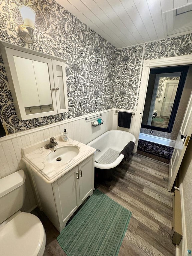 303 E 5th St, Washburn, WI 54891 - bathroom featuring wallpapered walls, a wainscoted wall, vanity, wood finished floors, and a freestanding bath