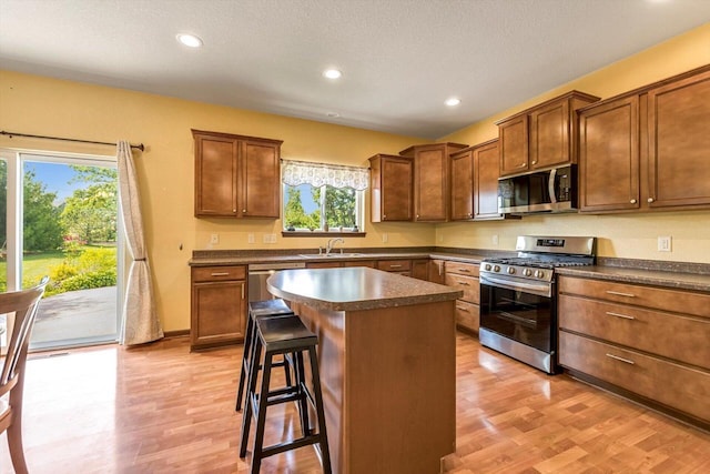 739 Pinehurst Dr, Mukwonago, WI 53149 - kitchen featuring stainless steel appliances, dark countertops, light wood-style floors, a breakfast bar, and recessed lighting