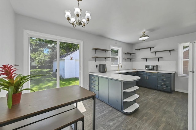 1007 14th Ave, Green Bay, WI 54304 - kitchen featuring open shelves, stainless steel microwave, dark wood-style floors, light countertops, and a chandelier