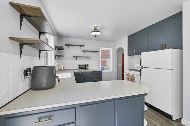 1007 14th Ave, Green Bay, WI 54304 - kitchen featuring white appliances, open shelves, light countertops, a peninsula, and dark wood-style flooring