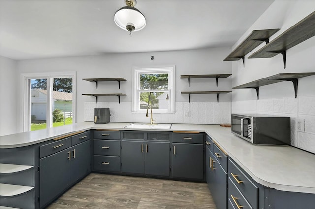 1007 14th Ave, Green Bay, WI 54304 - kitchen with open shelves, stainless steel microwave, a peninsula, light countertops, and dark wood finished floors