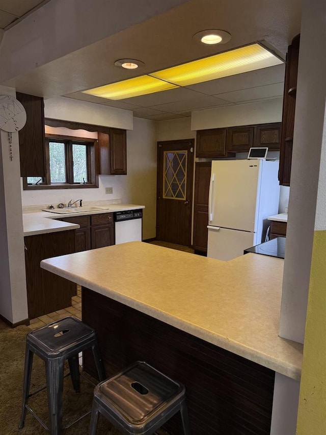 404 Prairie St, Mauston, WI 53948 - kitchen with freestanding refrigerator, dark brown cabinets, dishwashing machine, a kitchen bar, and recessed lighting