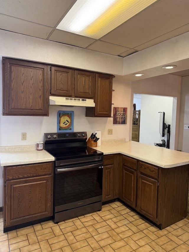 404 Prairie St, Mauston, WI 53948 - kitchen with black range with electric stovetop, under cabinet range hood, light countertops, a peninsula, and dark brown cabinetry