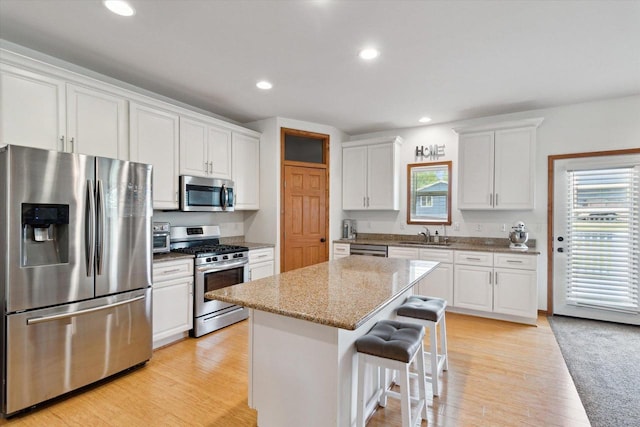 705 E Mason Dr, Edgerton, WI 53534 - kitchen with appliances with stainless steel finishes, white cabinetry, a kitchen island, light wood finished floors, and recessed lighting