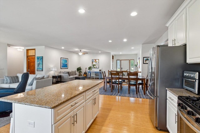 705 E Mason Dr, Edgerton, WI 53534 - kitchen with light wood-type flooring, recessed lighting, stainless steel gas stove, open floor plan, and white cabinets