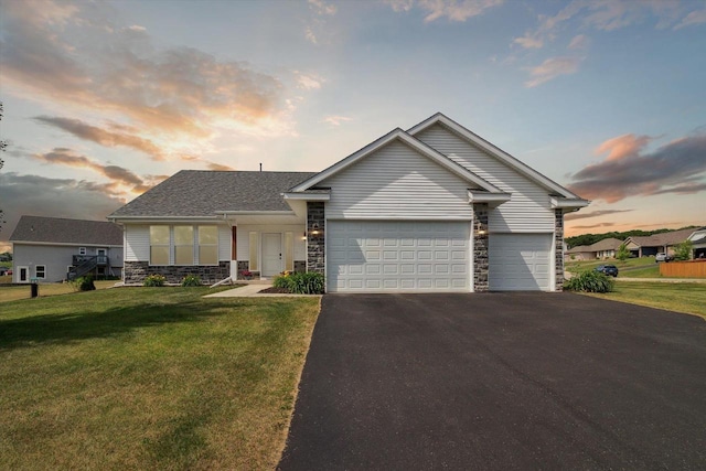 705 E Mason Dr, Edgerton, WI 53534 - view of front of home featuring stone siding, an attached garage, asphalt driveway, and a front lawn