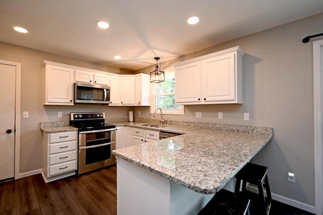 W355N5843 Bridle Ln, Oconomowoc, WI 53066 - kitchen featuring appliances with stainless steel finishes, a peninsula, white cabinets, a breakfast bar area, and recessed lighting