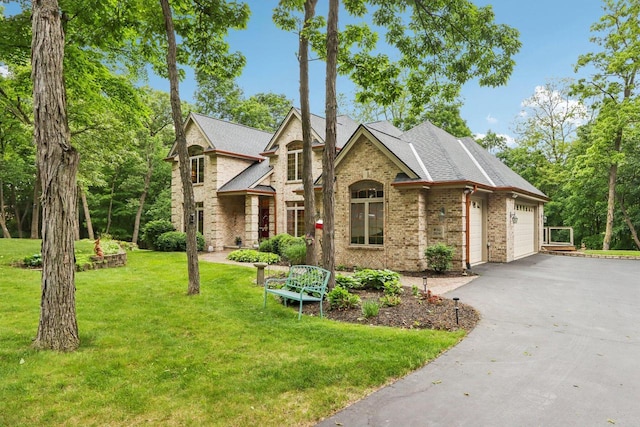 W332S9291 Red Brae Dr, Mukwonago, WI 53149 - tudor-style house with asphalt driveway, an attached garage, a front yard, brick siding, and a shingled roof