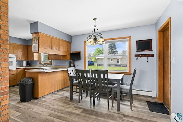 6D Hayes Ct, Superior, WI 54880 - kitchen featuring white oven, a peninsula, a chandelier, light countertops, and light wood-style floors