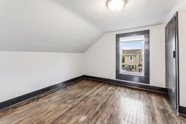 429 W Juneau St, Tomah, WI 54660 - additional living space featuring dark wood finished floors, vaulted ceiling, and a textured ceiling
