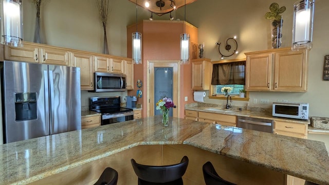 N100W17560 Whitetail Run, Germantown, WI 53022 - kitchen featuring stainless steel appliances, a breakfast bar area, light brown cabinets, a high ceiling, and light stone counters