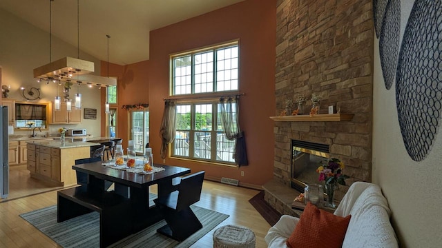 N100W17560 Whitetail Run, Germantown, WI 53022 - living area featuring light wood finished floors, high vaulted ceiling, a fireplace, and healthy amount of natural light