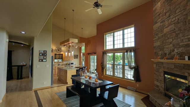 N100W17560 Whitetail Run, Germantown, WI 53022 - dining room with light wood-type flooring, high vaulted ceiling, ceiling fan, and a fireplace
