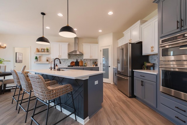 N56W24235 Torrey Pines Ln, Sussex, WI 53089 - kitchen with appliances with stainless steel finishes, wall chimney range hood, decorative backsplash, light countertops, and a kitchen breakfast bar