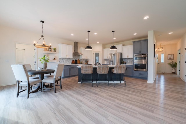 N56W24235 Torrey Pines Ln, Sussex, WI 53089 - kitchen with wall chimney range hood, stainless steel appliances, open shelves, light wood-type flooring, and recessed lighting