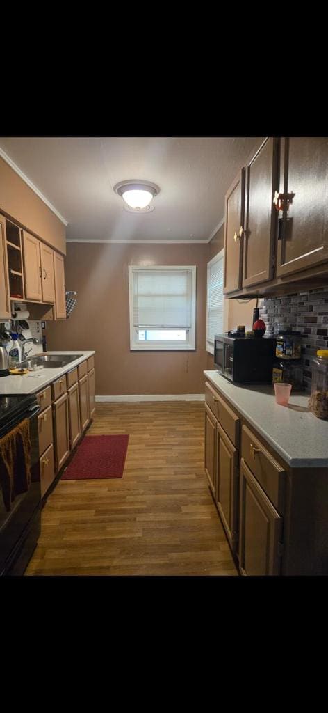 3416 S 66th St, Milwaukee, WI 53219 - kitchen with electric range, light wood-style flooring, decorative backsplash, crown molding, and light countertops