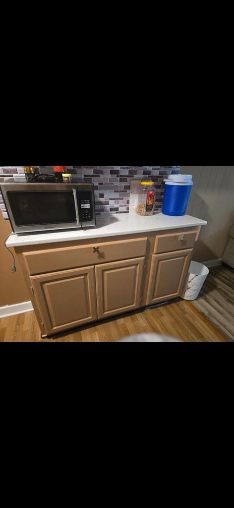 3416 S 66th St, Milwaukee, WI 53219 - kitchen view of stainless steel microwave, light countertops, light wood-style flooring, and decorative backsplash