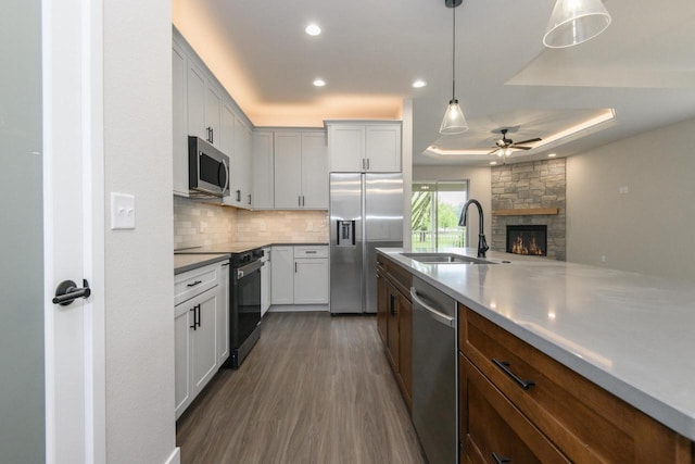 20900 Gray St, Lannon, WI 53046 - kitchen featuring stainless steel appliances, ceiling fan, tasteful backsplash, a fireplace, and a tray ceiling