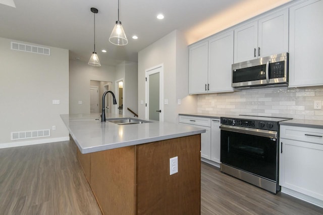 20900 Gray St, Lannon, WI 53046 - kitchen featuring stainless steel microwave, black electric range, dark wood finished floors, decorative backsplash, and recessed lighting
