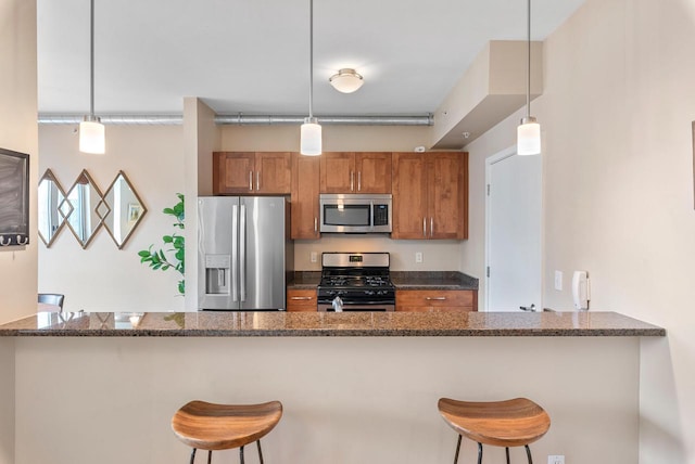 1541 N Jefferson St Unit 408, Milwaukee, WI 53202 - kitchen featuring appliances with stainless steel finishes, brown cabinetry, dark stone counters, and a peninsula