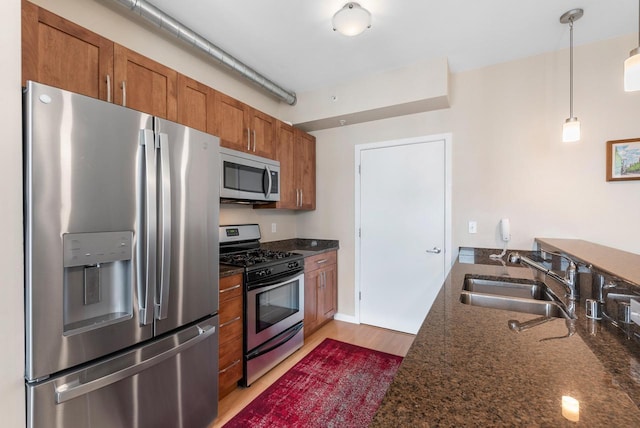 1541 N Jefferson St Unit 408, Milwaukee, WI 53202 - kitchen featuring stainless steel appliances, brown cabinetry, light wood-style flooring, a peninsula, and hanging light fixtures