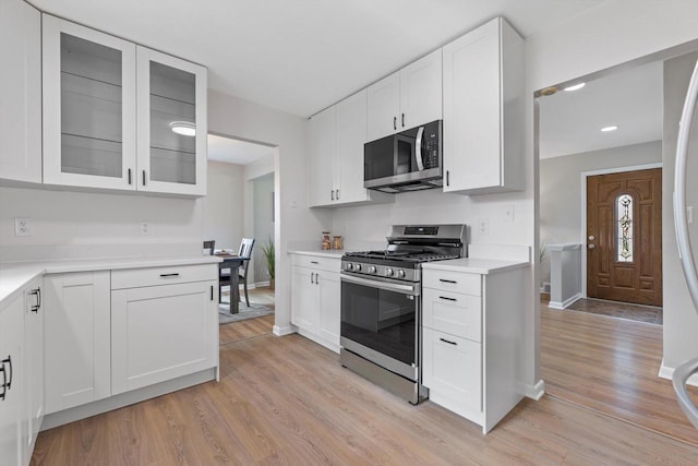4410 N 107th St, Milwaukee, WI 53225 - kitchen featuring stainless steel appliances, light wood-style floors, white cabinetry, light countertops, and glass insert cabinets