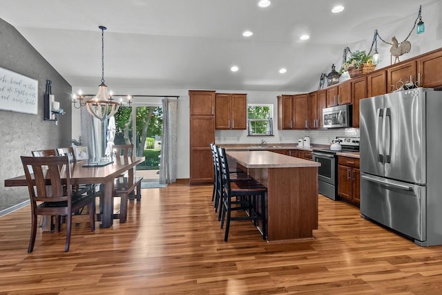 606 E Sheila Ave, Elkhorn, WI 53121 - kitchen featuring stainless steel appliances, vaulted ceiling, a chandelier, light wood-style flooring, and a center island