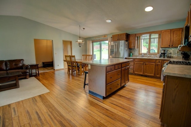 N4374 Esther Dr, Onalaska, WI 54650 - kitchen with appliances with stainless steel finishes, a chandelier, a breakfast bar area, vaulted ceiling, and brown cabinets