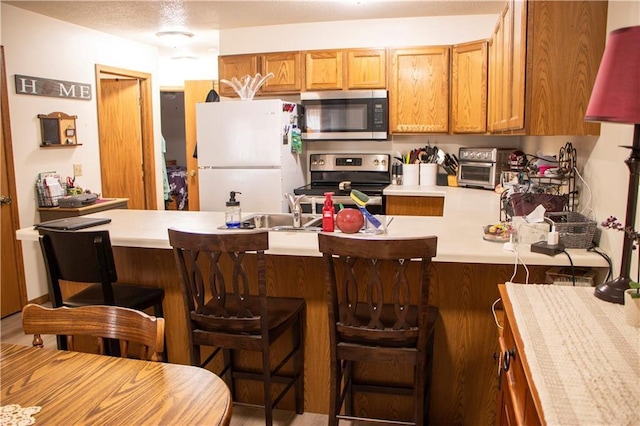 3155 Craig Rd Unit 3155, Eau Claire, WI 54701 - kitchen with appliances with stainless steel finishes, a peninsula, light countertops, a kitchen breakfast bar, and brown cabinets