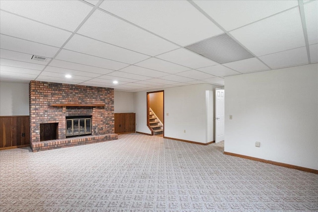 1125 W State St, Marshfield, WI 54449 - unfurnished living room with a drop ceiling, a fireplace, stairs, wood walls, and carpet floors