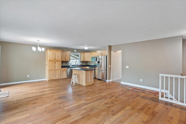 1125 W State St, Marshfield, WI 54449 - kitchen featuring appliances with stainless steel finishes, light brown cabinets, a chandelier, dark countertops, and a kitchen island