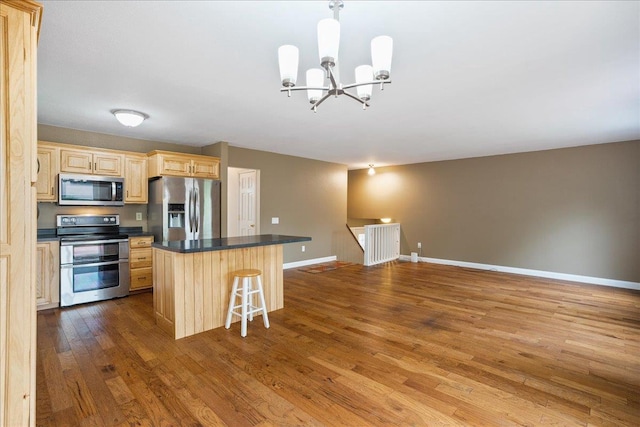 1125 W State St, Marshfield, WI 54449 - kitchen with appliances with stainless steel finishes, light brown cabinets, wood finished floors, a chandelier, and a kitchen bar