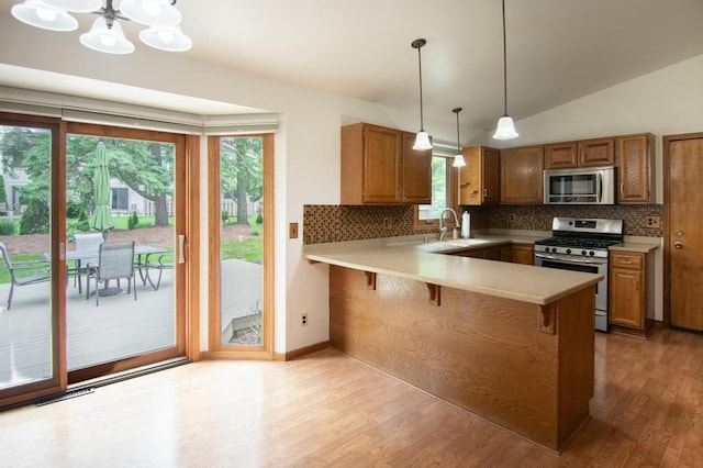 5947 Pilgrim Way, Mount Pleasant, WI 53406 - kitchen featuring stainless steel appliances, a peninsula, backsplash, light wood-style flooring, and vaulted ceiling