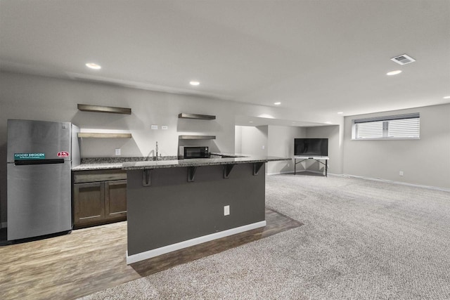 405 Blue Moon Dr, Verona, WI 53593 - kitchen featuring freestanding refrigerator, a kitchen breakfast bar, dark stone counters, recessed lighting, and black microwave
