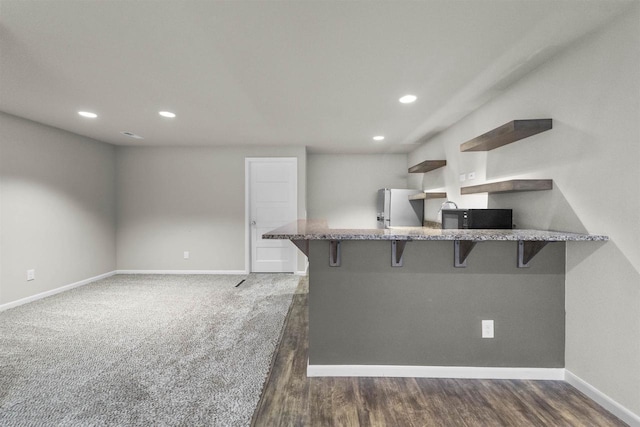 405 Blue Moon Dr, Verona, WI 53593 - kitchen featuring freestanding refrigerator, a breakfast bar area, black microwave, stone countertops, and recessed lighting