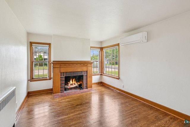 120 W 12th St, Ashland, WI 54806 - unfurnished living room featuring a wall mounted AC, radiator heating unit, a brick fireplace, and wood finished floors