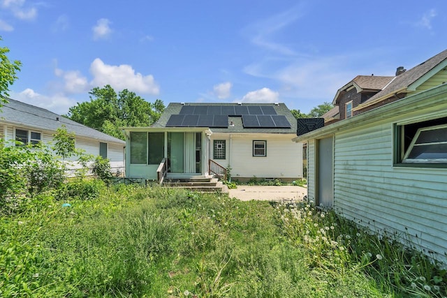 4951 N 49th St, Milwaukee, WI 53218 - rear view of house with roof mounted solar panels, roof with shingles, and a sunroom