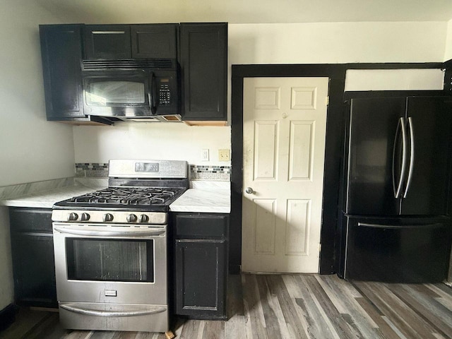 4668 N 29th St, Milwaukee, WI 53209 - kitchen with freestanding refrigerator, gas range, black microwave, and dark cabinetry
