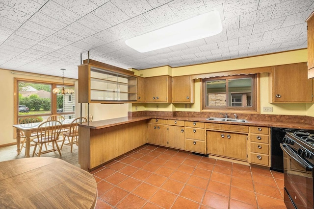 2908 Prais St, Stevens Point, WI 54481 - kitchen featuring black range with gas cooktop, dark countertops, tile patterned flooring, hanging light fixtures, and brown cabinets